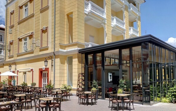A yellow building with a glass conservatory and outdoor seating area. - Hotel Continental (Opatija)