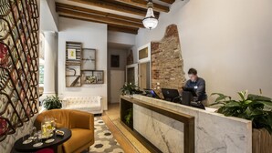 Un espace d’accueil comprenant un comptoir en marbre, un canapé et une table basse avec des boissons.