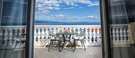 A balcony with a table and chairs, a view of the sky and distant landscape.
