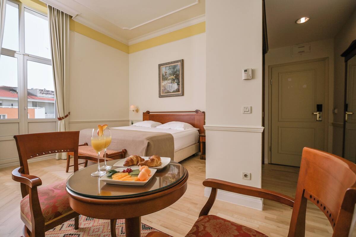Ein Hotelzimmer mit einem Bett, einem Esstisch mit Frühstück und Blick nach draußen.