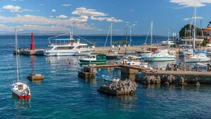 Un port de plaisance où sont amarrés différents types de bateaux, une jetée et un ciel dégagé.