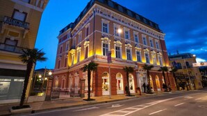 Un bâtiment historique à l’architecture riche et travaillée, doté de grandes fenêtres et d’une façade bien éclairée.