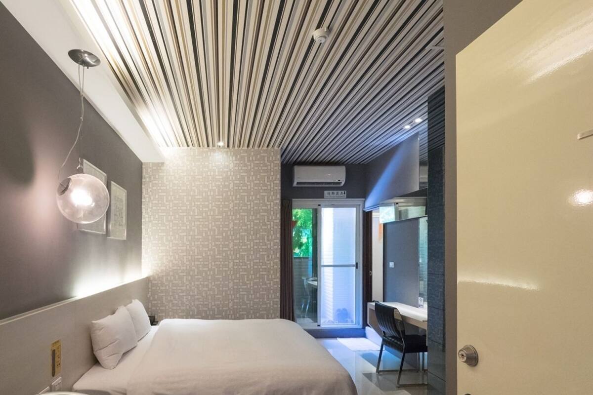 Een moderne slaapkamer met een groot bed, een stoel en een bureau.