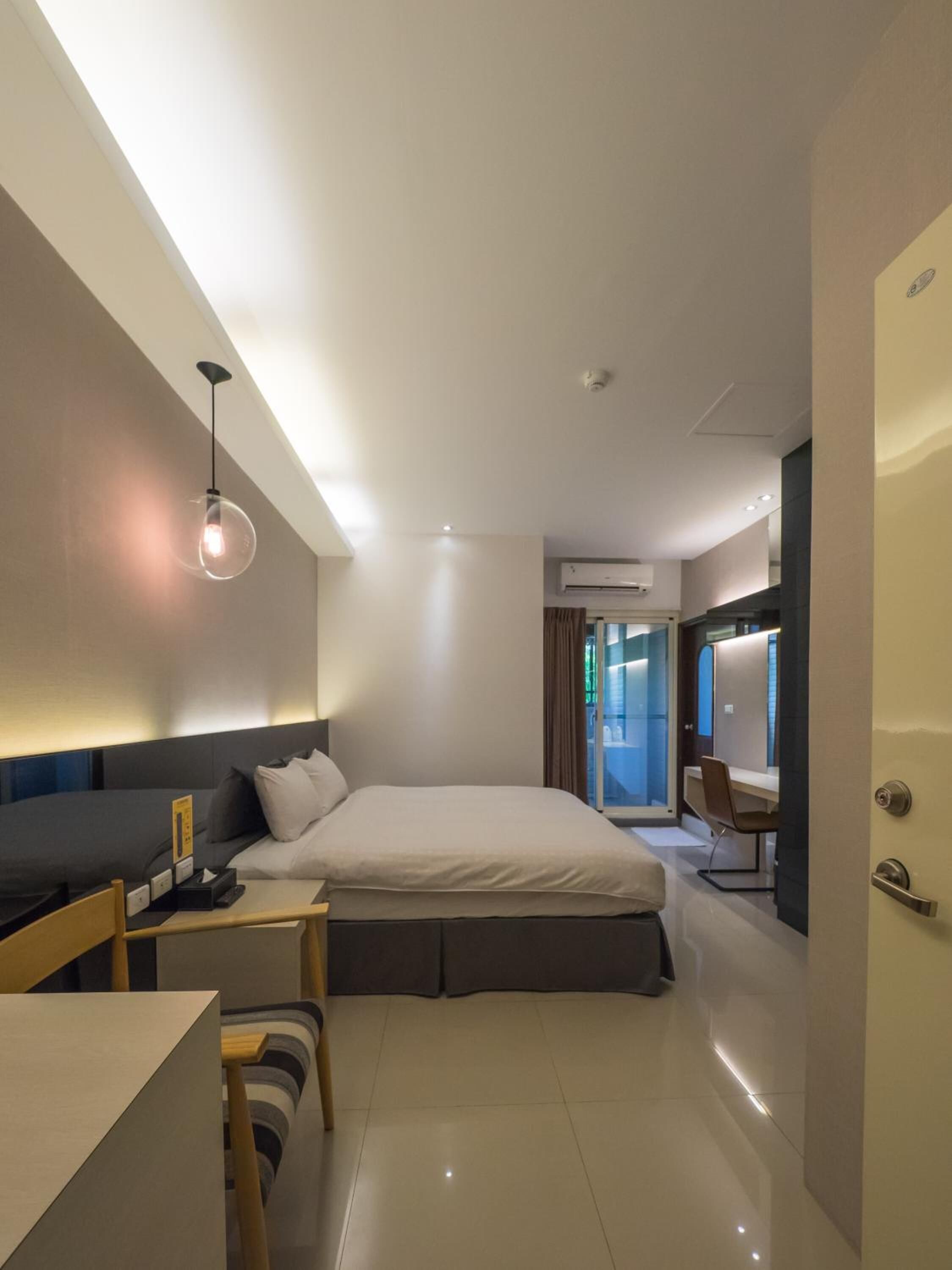 Ein modernes Hotelzimmer mit einem großen Bett, einem Nachttisch und einer Schreibtischzeile.