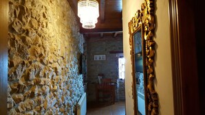 A narrow stone corridor with a wooden chair and a framed mirror.