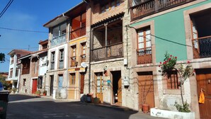 A row of traditional buildings with balconies, some with plants, and a clear sky.
