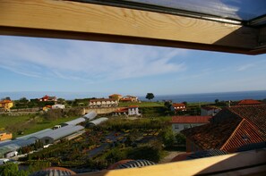 A view of a coastal village with traditional houses, a greenhouse, and a clear sky. - El Juacu (Llanes)