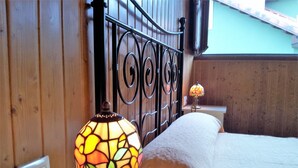 A bed with a white comforter, a bedside lamp with a stained glass shade, and a wooden headboard.