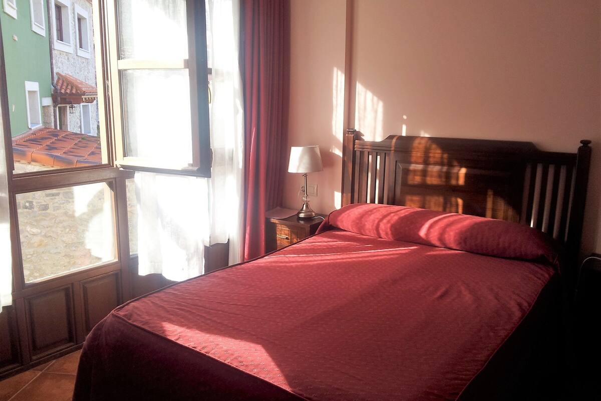Una cama individual con cabecera de madera en una habitación con ventana.