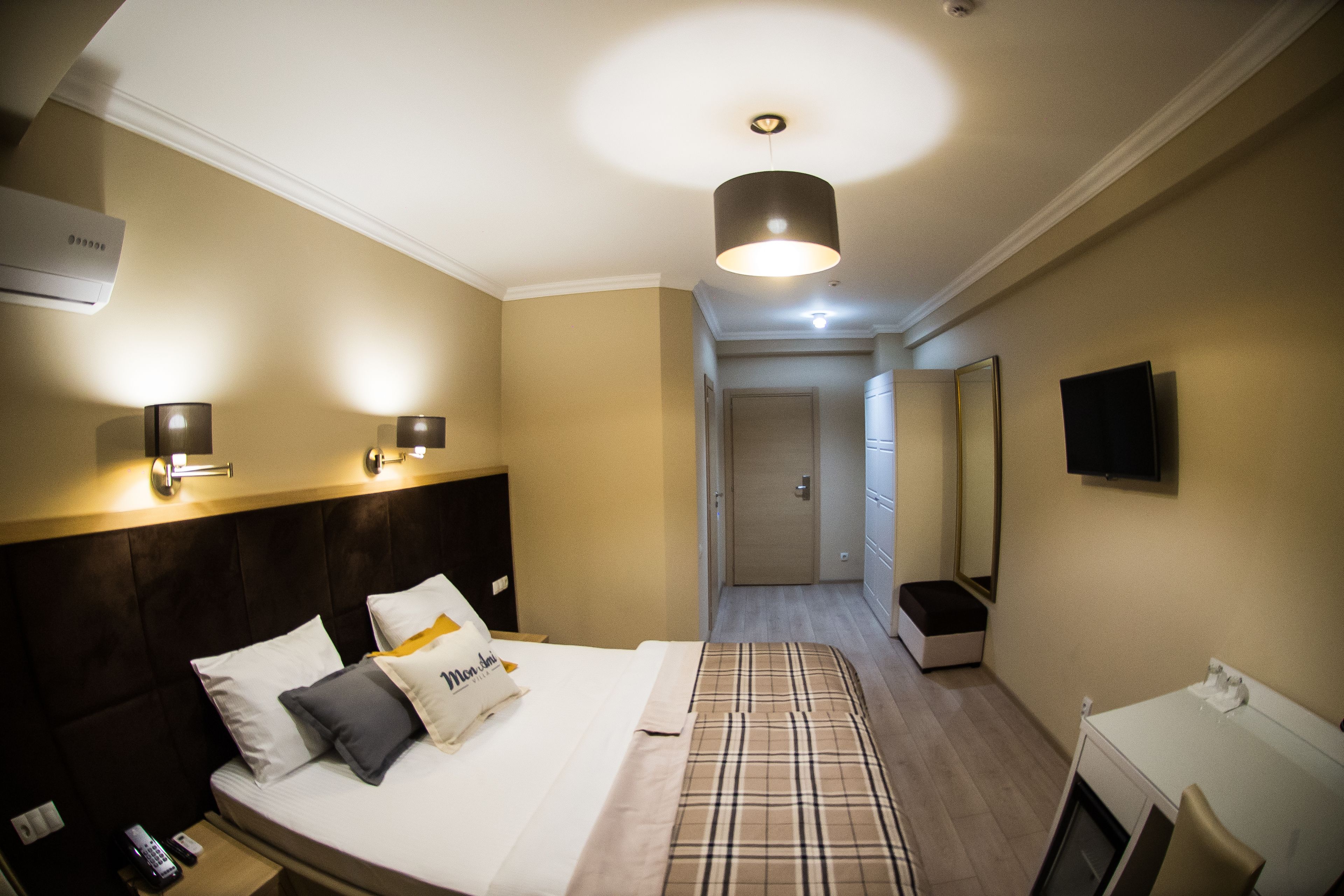 Habitación de hotel con cama, lámparas de noche, televisión y baño a la vista.