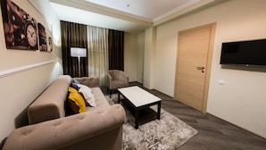 A modern living room with a sofa, armchair, coffee table, and a TV on the wall. - Mon Ami Villa (Chisinau)
