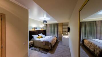 Una habitación de hotel moderna con una cama grande, mesitas de noche, un escritorio y un espejo.