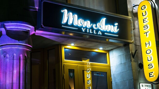 A hotel entrance with a neon sign reading "Mon Ami Villa" and a "Guest House" sign. - Mon Ami Villa (Chisinau)