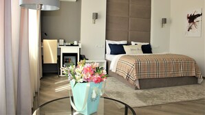 A modern hotel room with a large bed, a desk, and a glass table with a bouquet of flowers. - Mon Ami Villa (Chisinau)