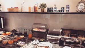 A buffet setup with various food items, beverages, and condiments. - Mon Ami Villa (Chisinau)