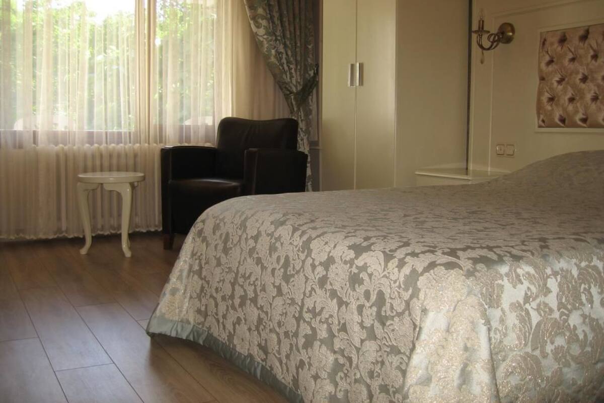 Un dormitorio con una cama grande, una silla, un armario y una mesita.