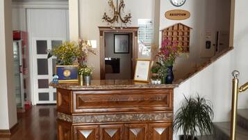 A reception desk with a framed certificate, a clock, and a sign indicating the reception area.