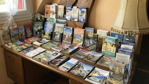 Uma mesa de madeira com vários livros e folhetos de viagem, alguns com imagens de castelos e paisagens.
