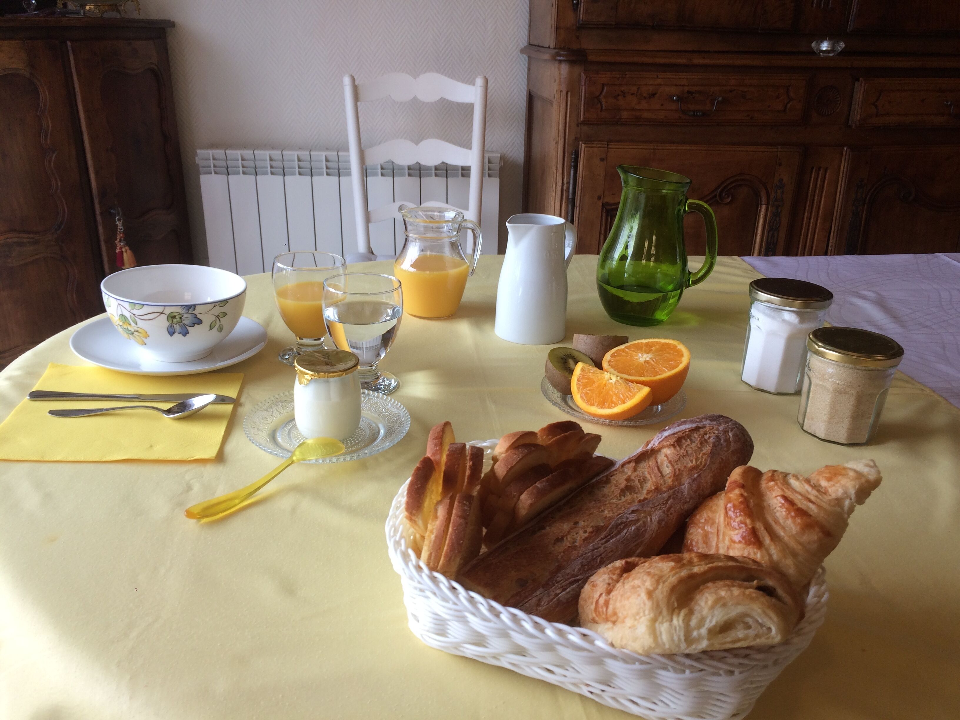 Une table de petit-déjeuner avec du pain, des viennoiseries, des fruits et des boissons.
