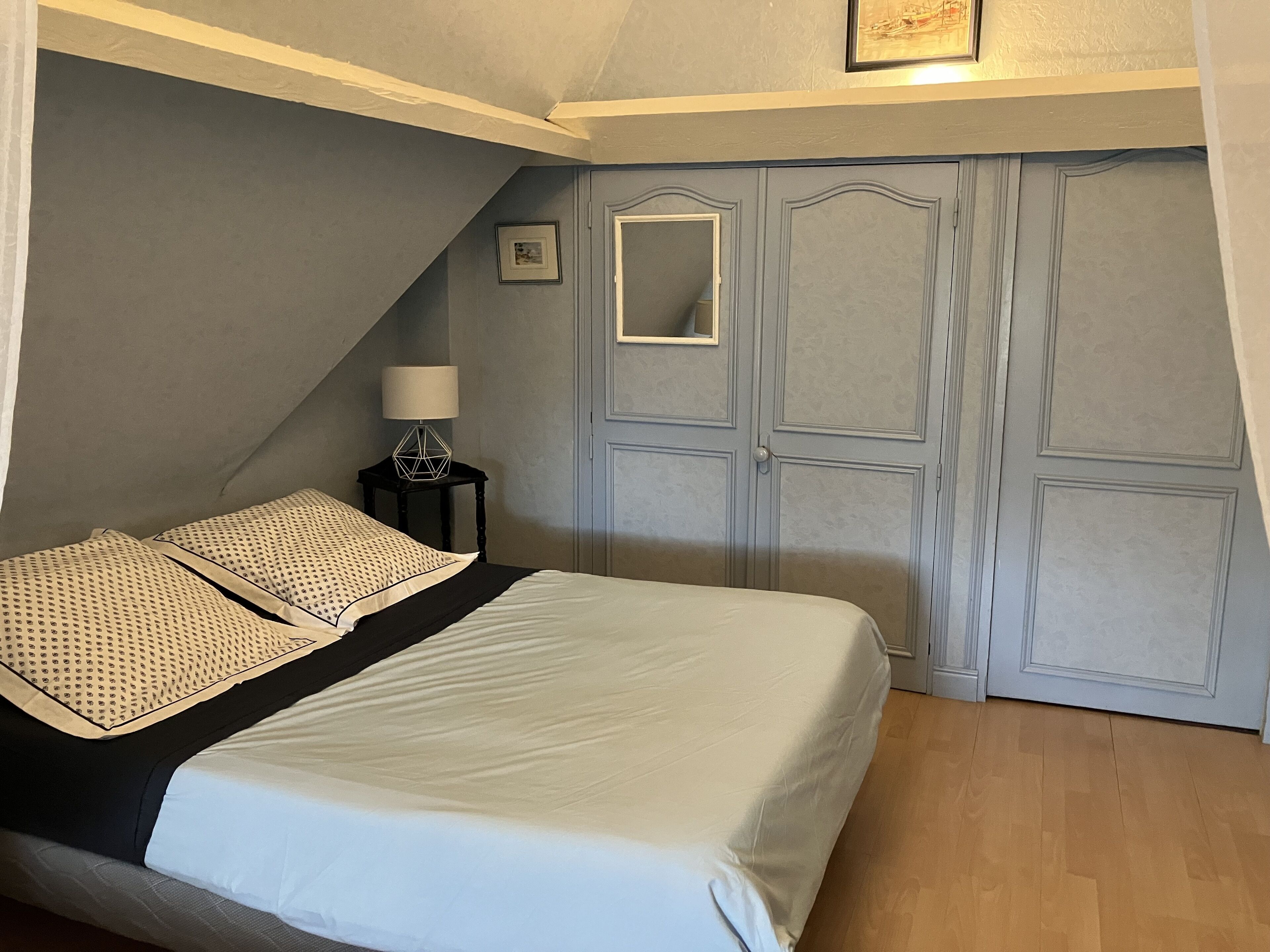 Ein Schlafzimmer mit einem Bett, einem Nachttisch, einer Lampe und einem Kleiderschrank.