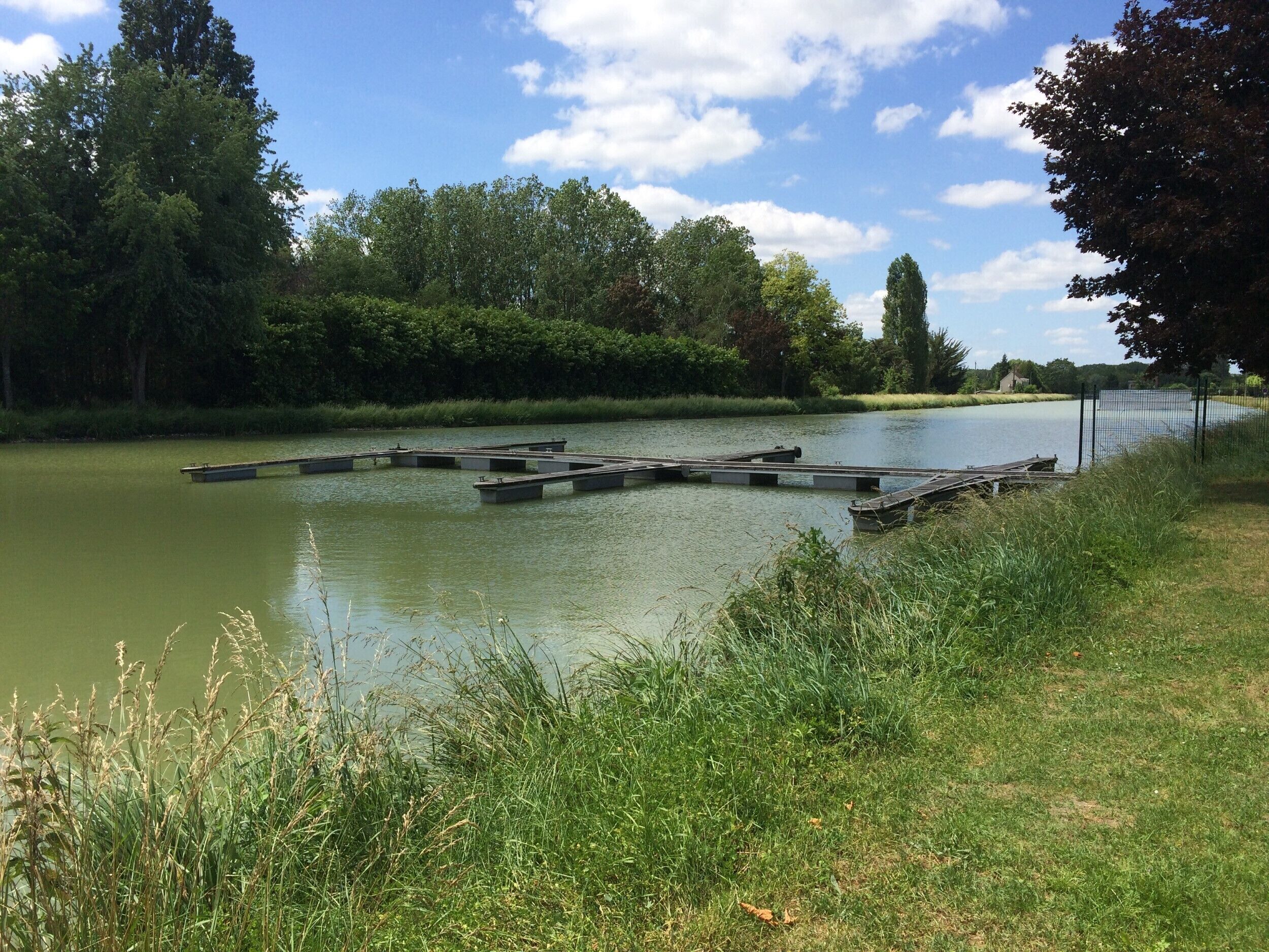 A calm river with a wooden dock extending into the water.