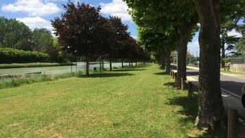 A park with a grassy area, trees, a fence, and a body of water.