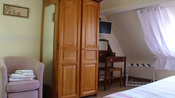 Une chambre à coucher avec une armoire en bois, un bureau avec un ordinateur, une chaise, un lit et une fenêtre avec des rideaux.