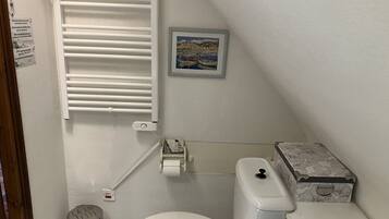 A small, compact bathroom with a toilet, bidet, and a radiator.