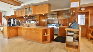 A spacious kitchen with wooden cabinetry, a central island, and a breakfast bar. - Hotel Gasthof Roessle (Rottenburg)
