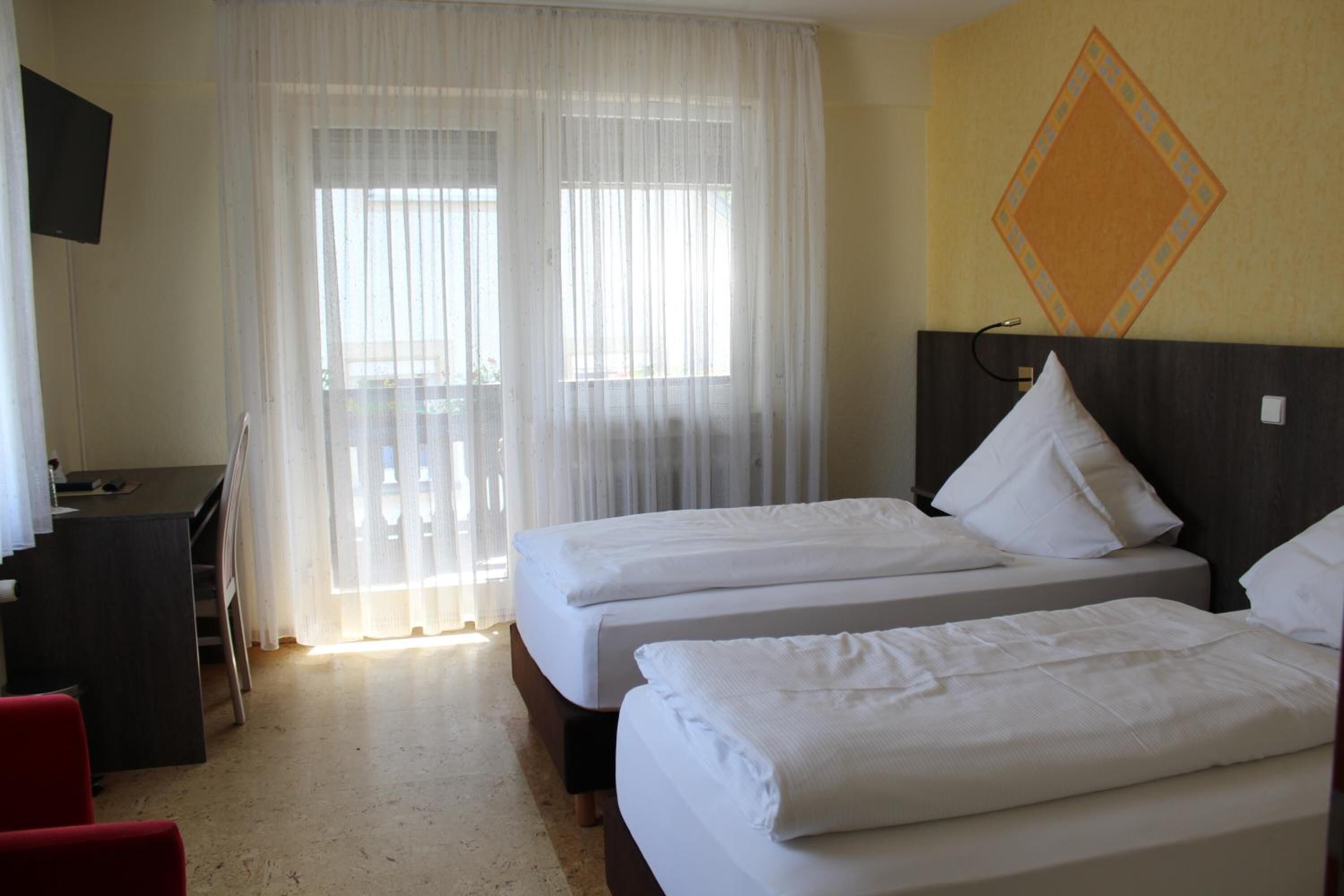 A hotel room with two beds, a desk, and a TV.