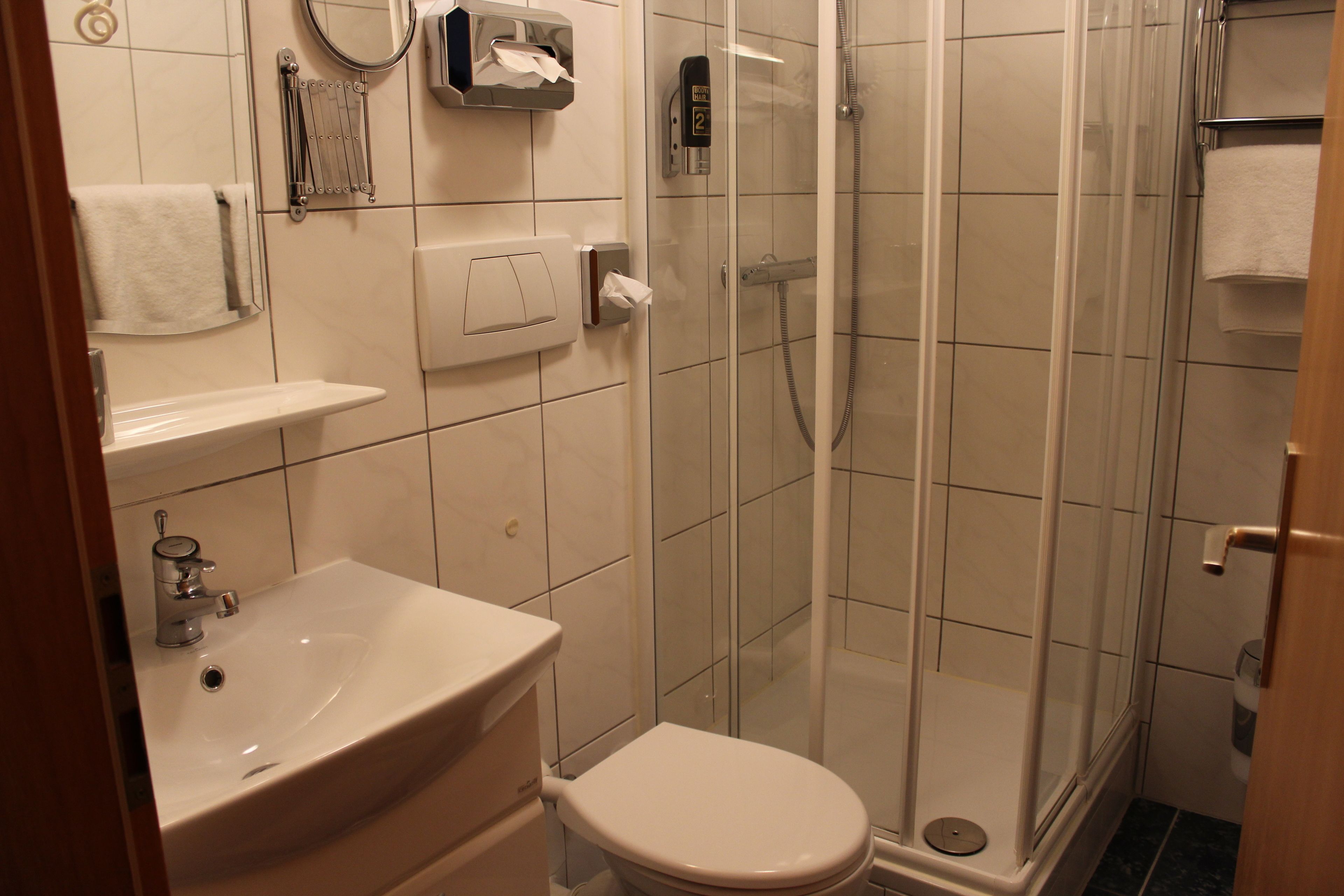 Un baño con lavamanos, inodoro y ducha envuelta en vidrio.