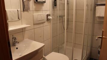 Un baño con lavamanos, inodoro y ducha envuelta en vidrio.