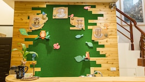 Eine Wand mit Holzausschnitten und grünem Kunstgrün, verziert mit verschiedenen Tier- und Pflanzenformen.