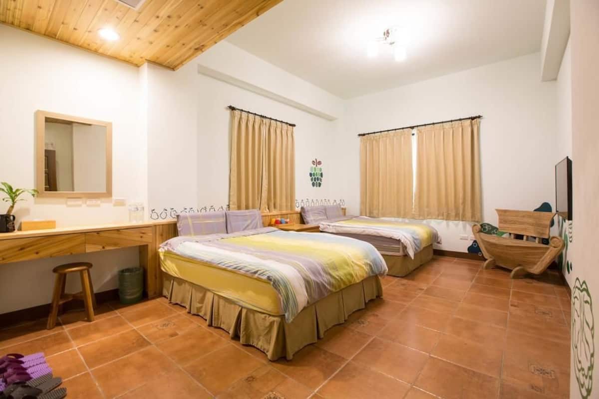Une chambre avec deux lits, un bureau, un miroir et une télévision.