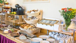 Een buffet met diverse gerechten, waaronder brood, gebak en fruit.