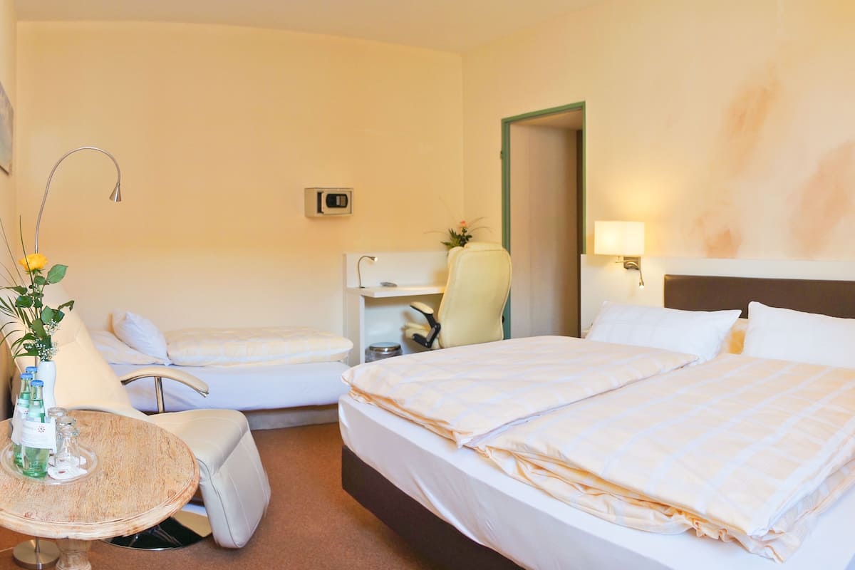 Een hotelkamer met een bed, een bureau, een stoel en een klein tafeltje met een bloemenvaas.