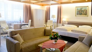 Een hotelkamer met een bank, een bed, een bureau en een schilderij aan de muur.