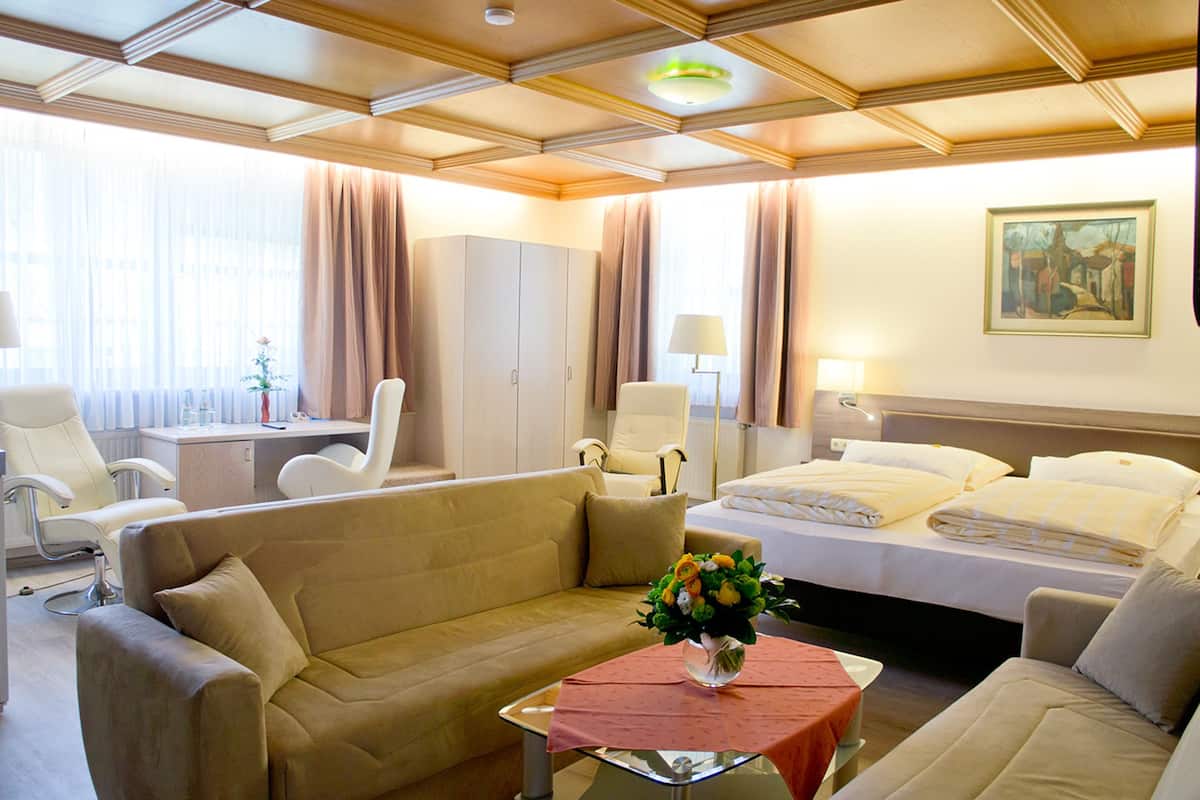 Een hotelkamer met een bank, een bed, een bureau en een schilderij aan de muur.