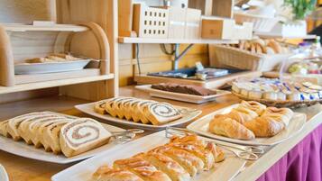 A buffet with various pastries and bread, including croissants and rolls.