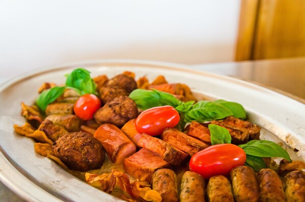 A plate of food with sausages, tomatoes, and basil.