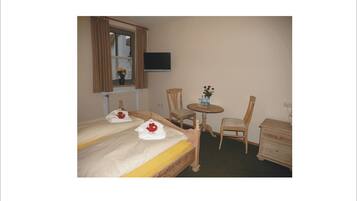 A hotel room with two beds, a small round table, a chair, and a dresser.