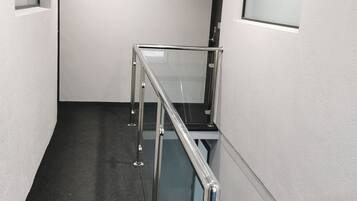A modern interior with a glass railing, a dark floor, and white walls.