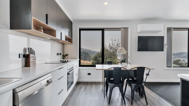 A modern kitchen with a dining area, large windows, and a view of the outdoors. - Youngtown Executive Apartments (Youngtown)