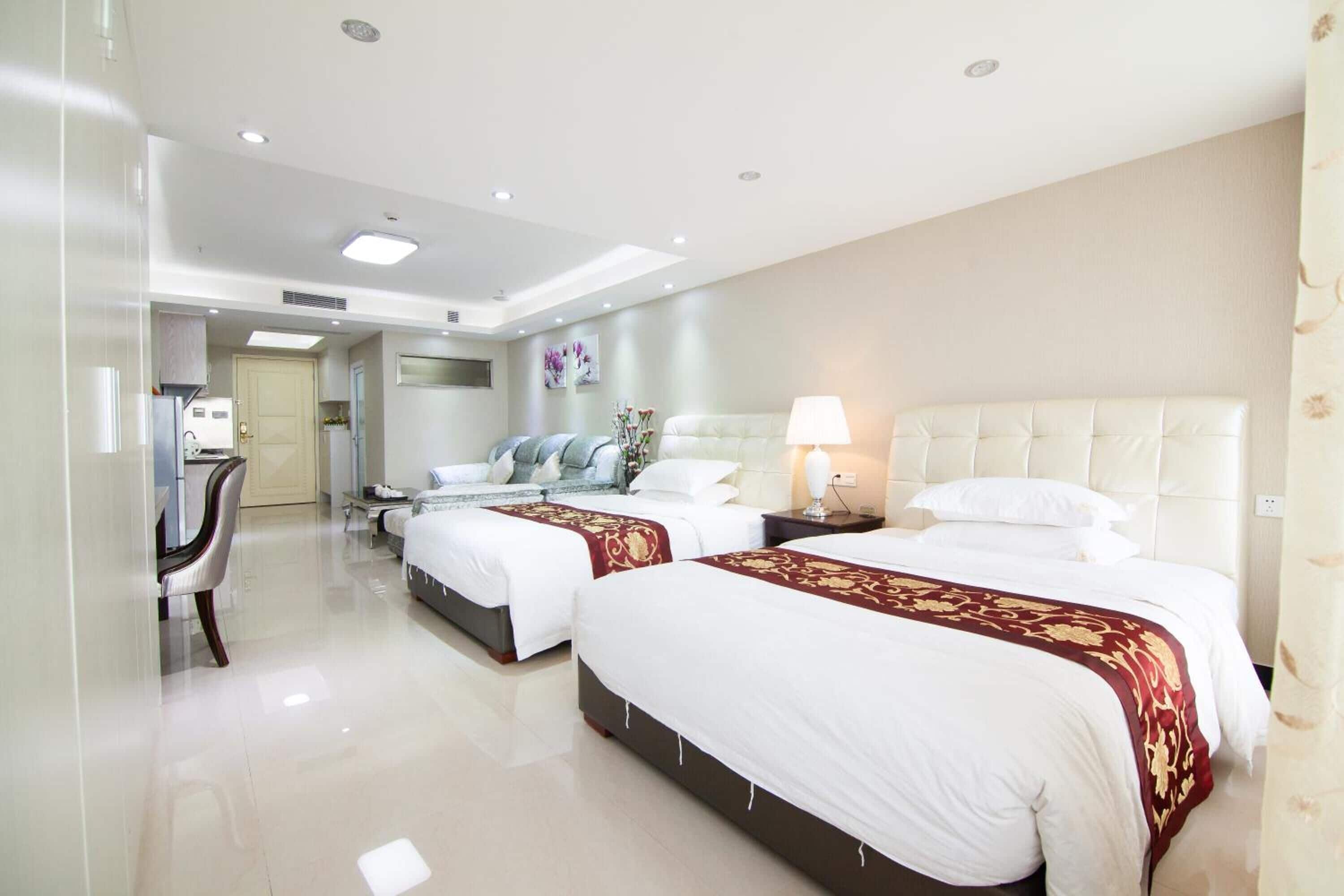 A hotel room with two beds, a sitting area, and a kitchenette.