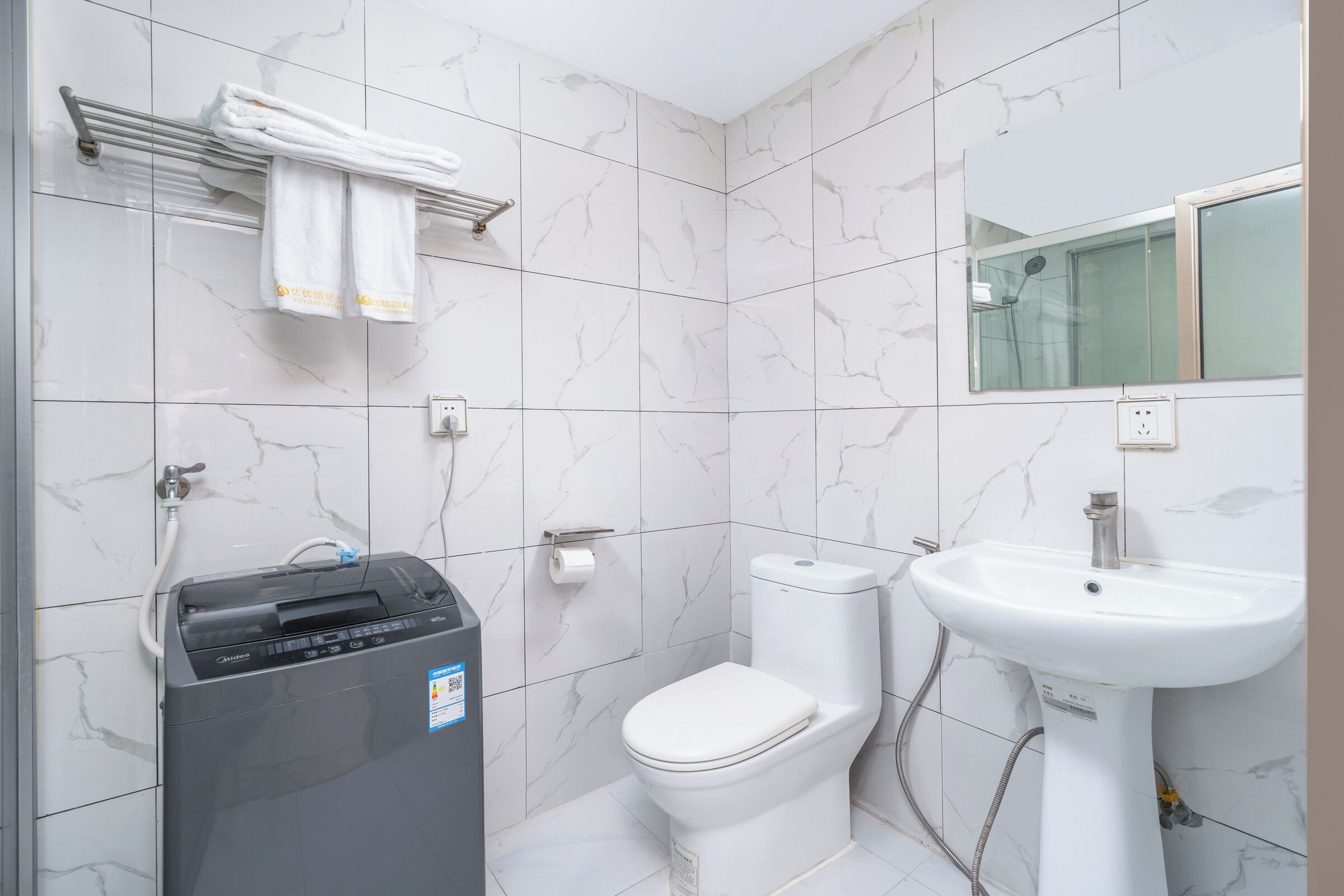 Un baño con inodoro, bidé, lavabo y toallero.
