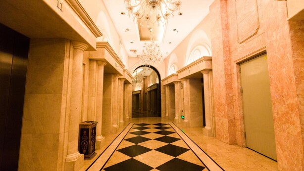 A hotel corridor with marble floors, columns, and a chandelier. - YOYO International Apartment (Guangzhou)