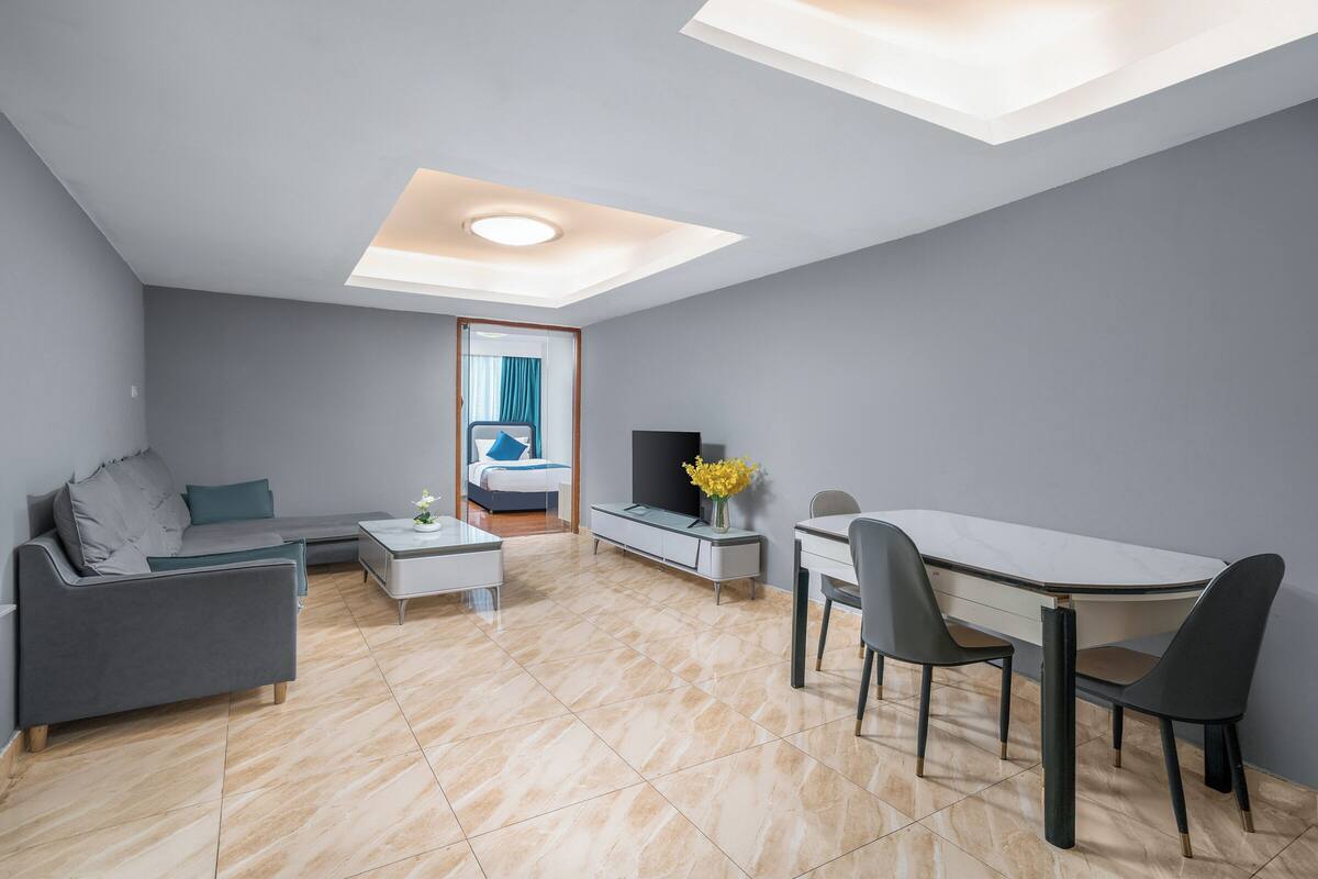 A modern living room with a sofa, coffee table, TV stand, and dining area.