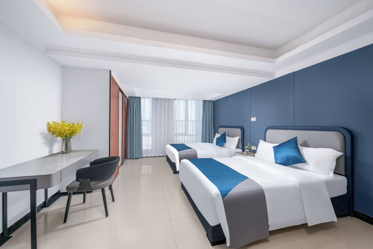 A hotel room with two beds, a desk, and a chair.