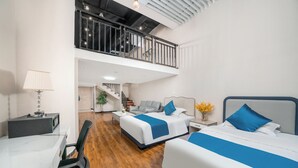 A hotel room with two beds, a desk, a chair, a lamp, and a staircase leading to an upper level. - YOYO International Apartment (Guangzhou)