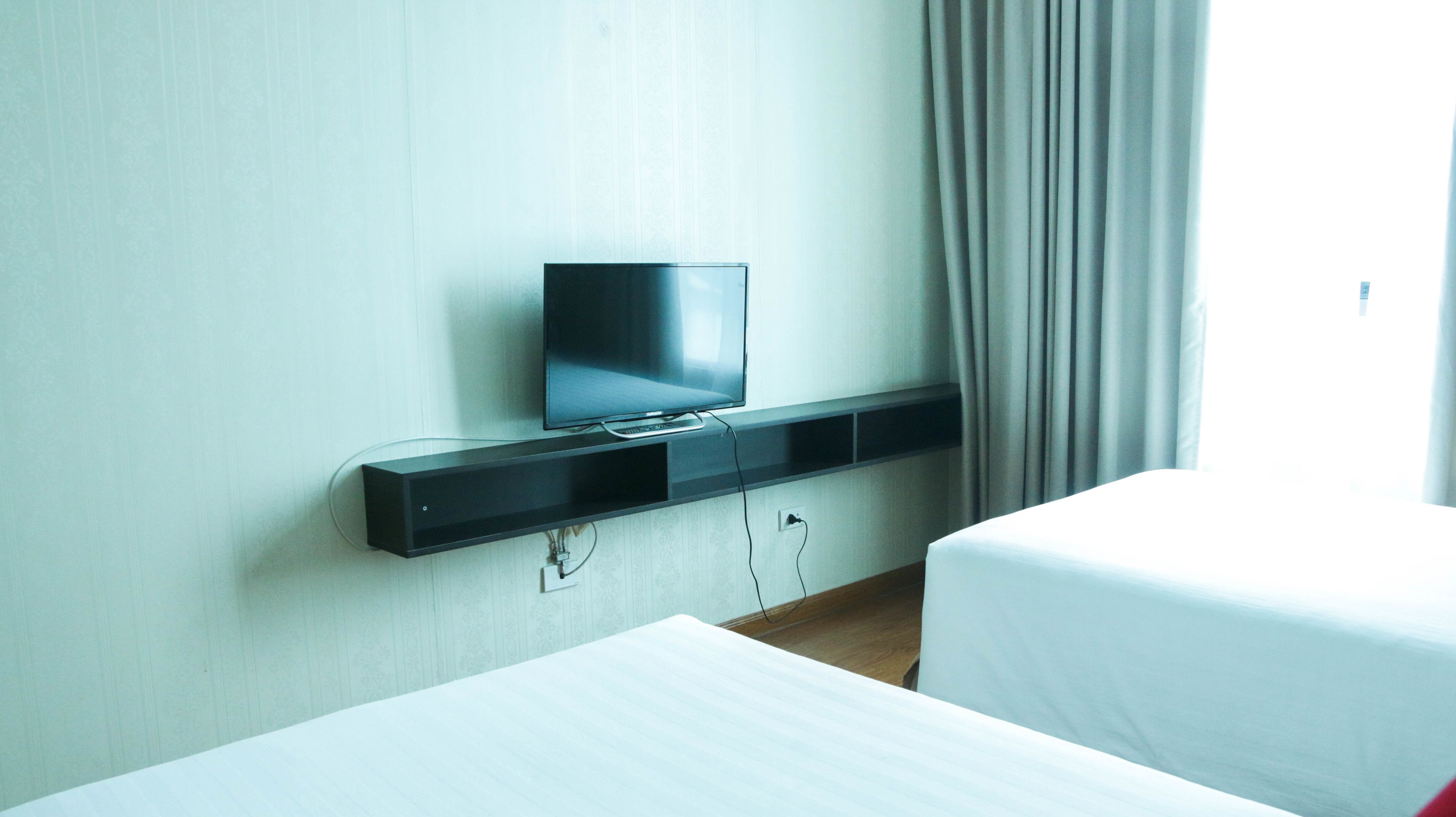 Une chambre d’hôtel équipée d’un téléviseur à écran plat fixé au mur, d’une table de chevet et d’un lit.